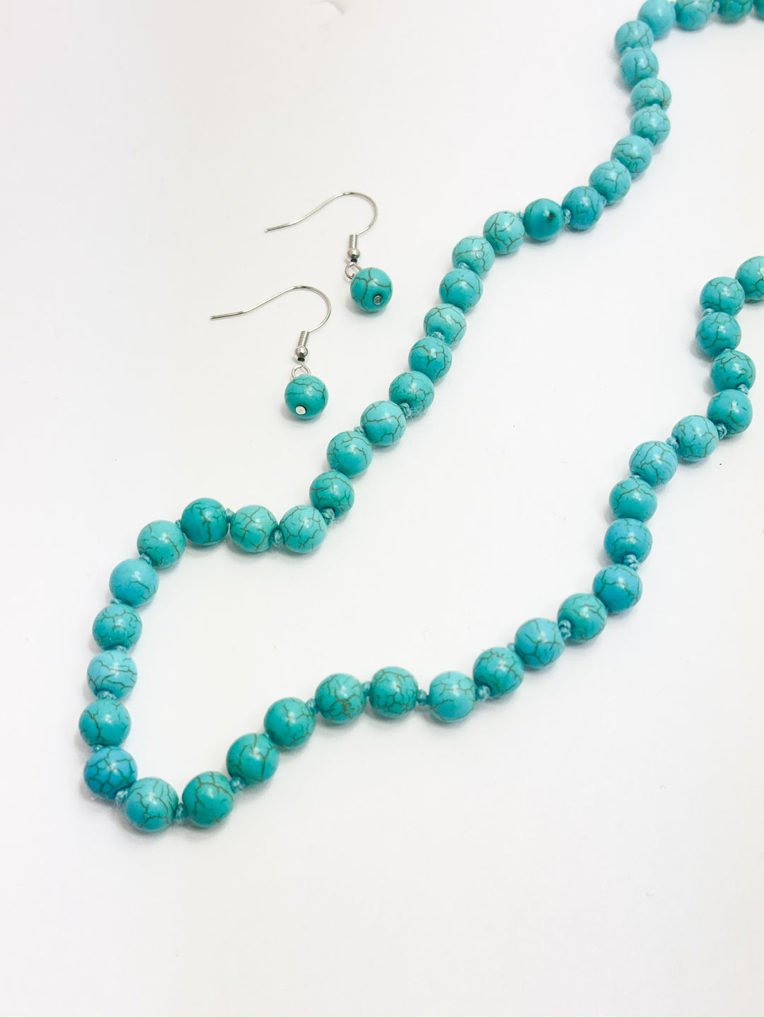 A turquoise bead strand necklace with a matching pair of beaded earrings, displayed on a white background.
