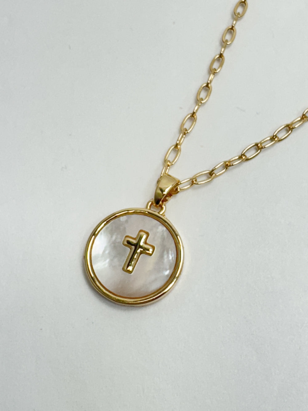Gold necklace with a cross pendant on a white background