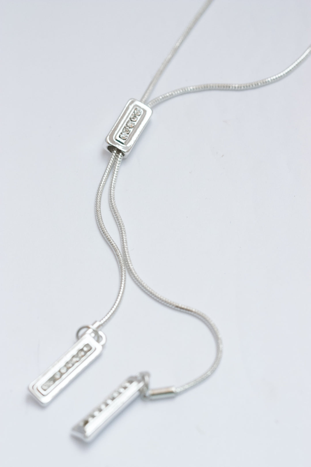 Silver necklace with three pendant charms on a light gray background