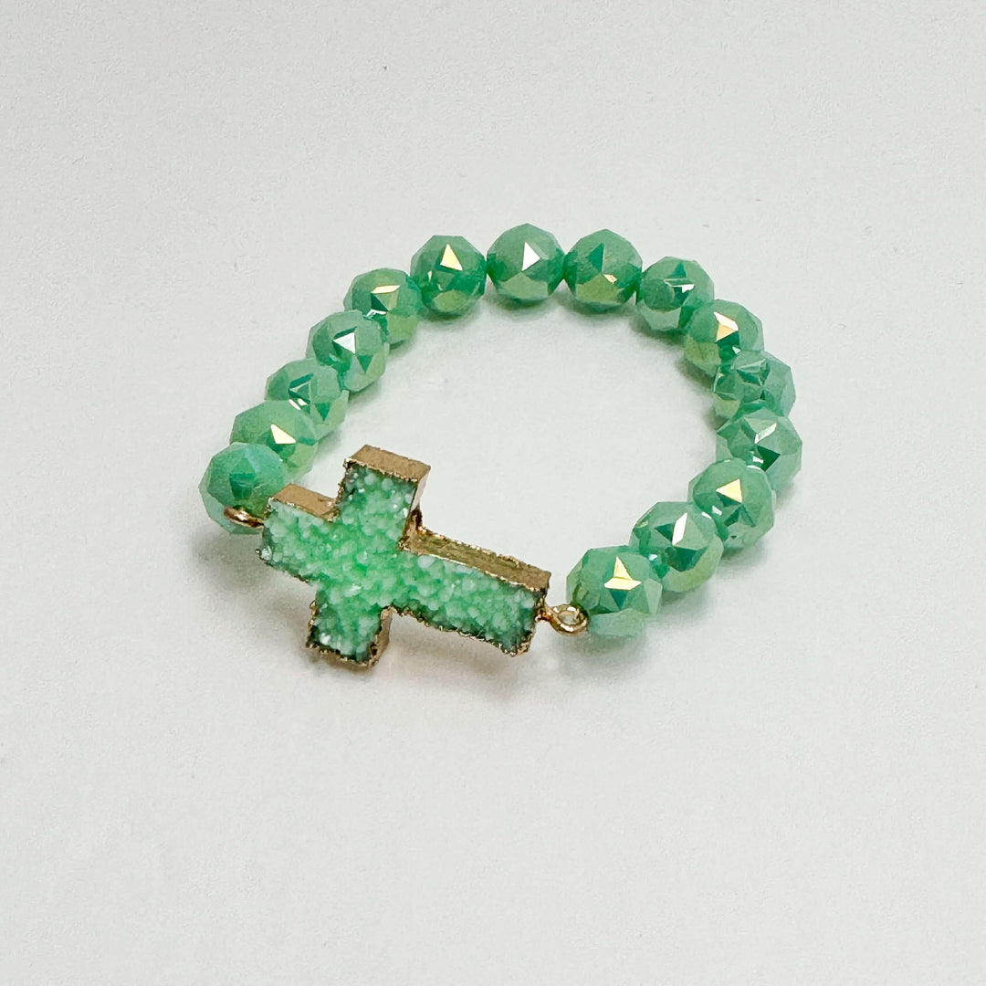 faceted green beaded bracelet with druzy cross detail on white background