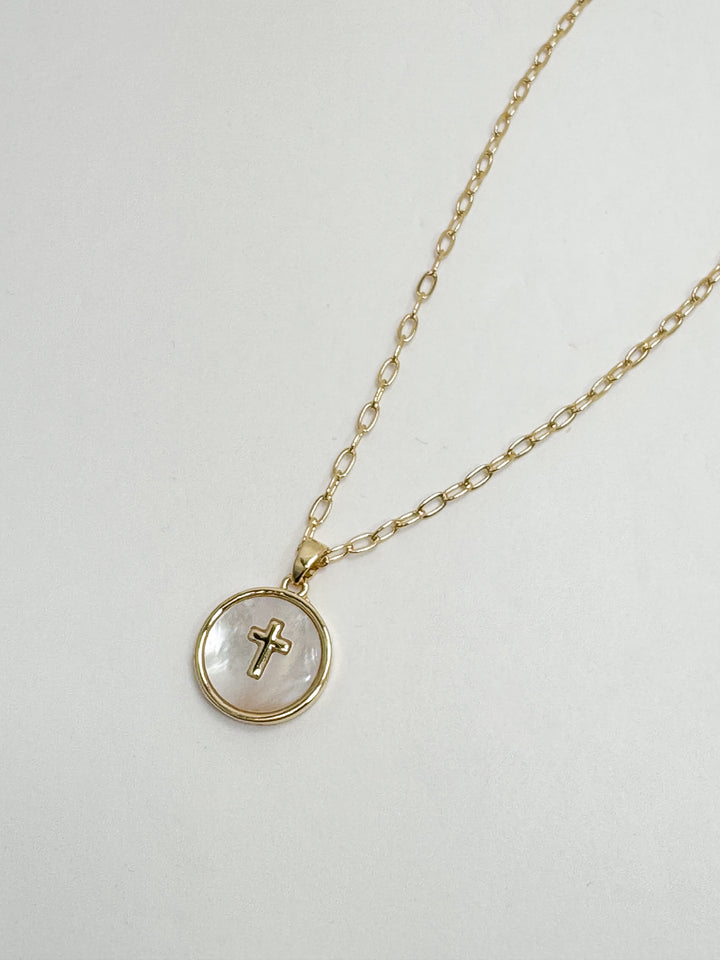 Gold necklace with a round pendant featuring a cross