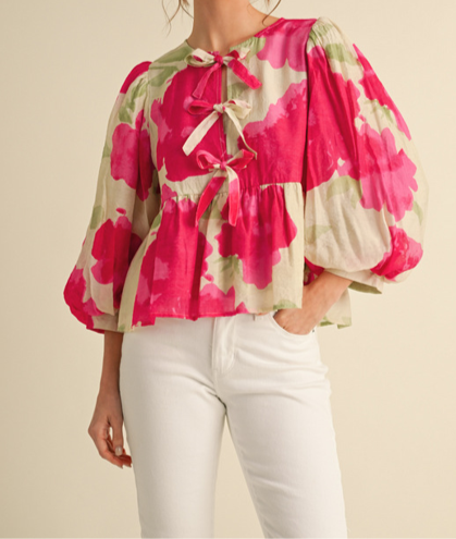 Woman wearing a floral blouse with pink and green pattern on a beige background