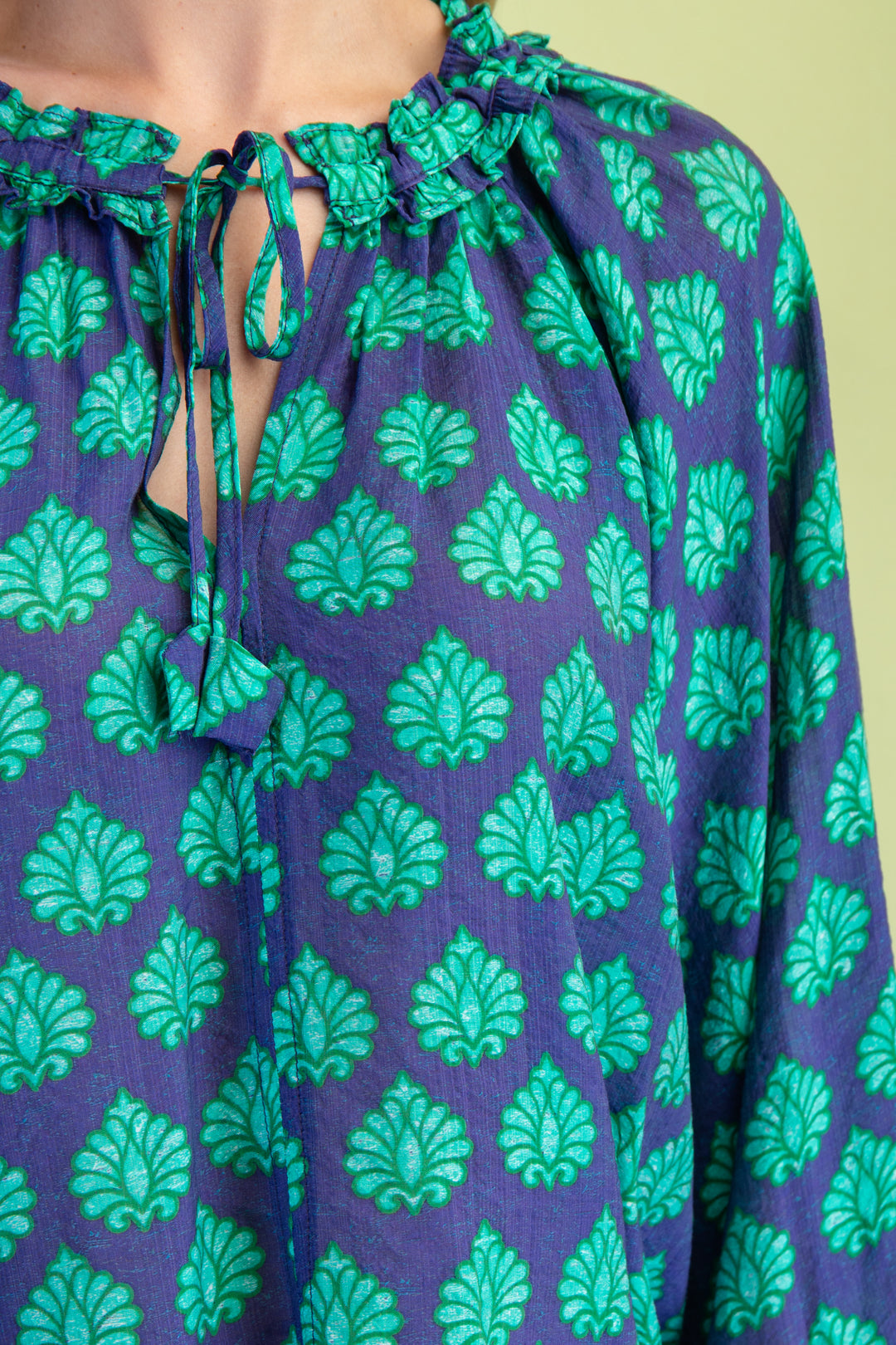 Purple blouse with green leaf pattern on a yellow background