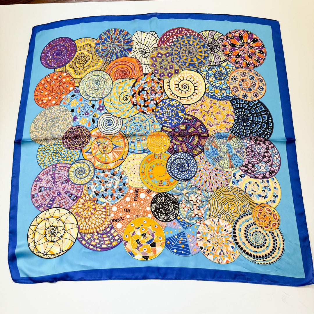 A multicolored scarf with a geometric pattern, primarily in blue, laying on white background