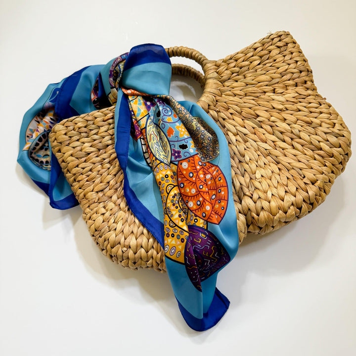 A multicolored scarf with a geometric pattern, primarily in blue, draped over a woven basket.