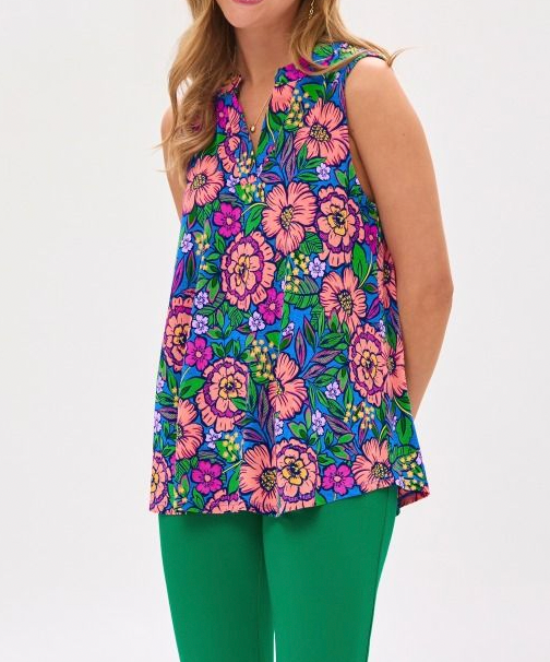 Woman wearing a colorful floral sleeveless top and green pants on a white background