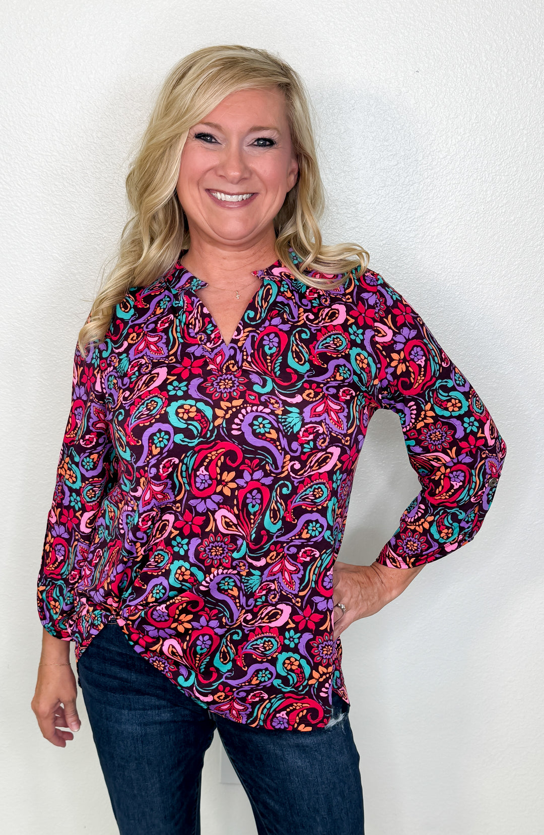 Woman wearing a colorful paisley shirt against a white background