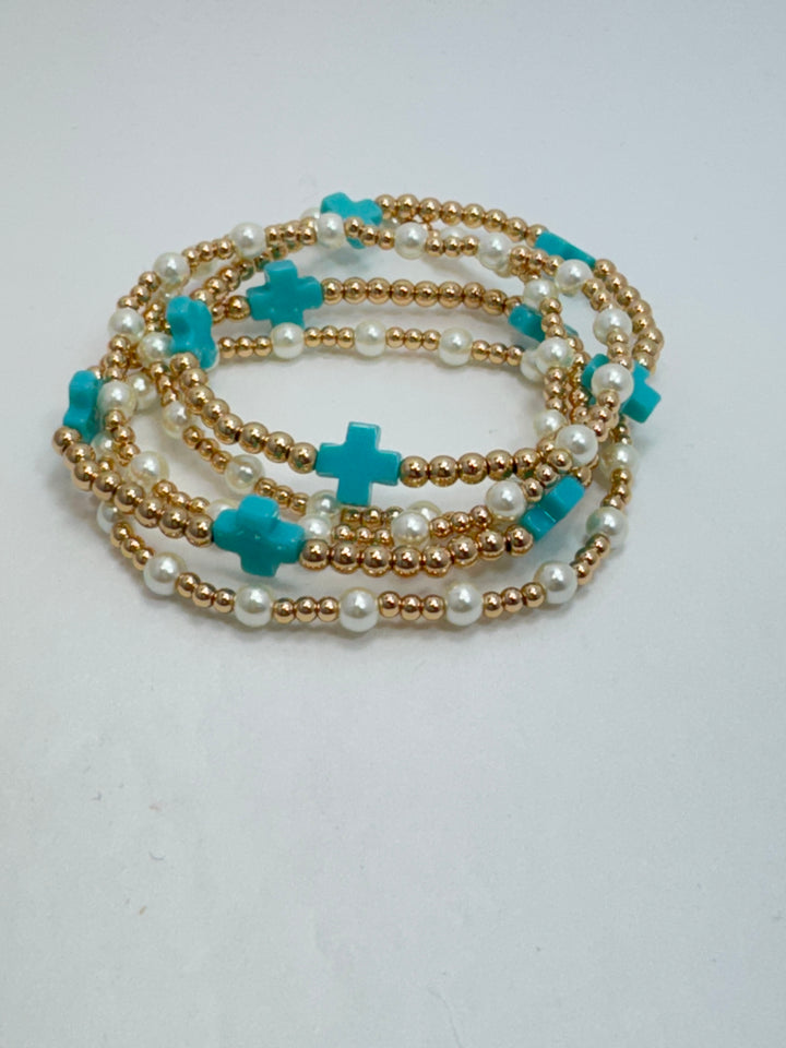 Necklace with gold chain, pearls, and turquoise crosses on a white background