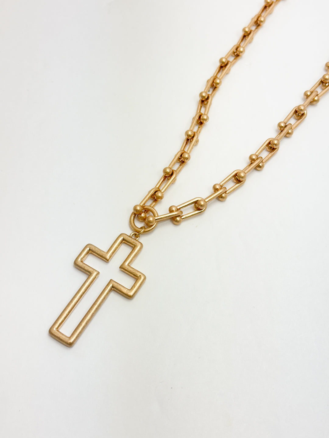 Gold chain necklace with a cross pendant on a white background