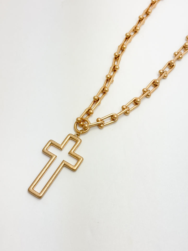 Gold chain necklace with a cross pendant on a white background
