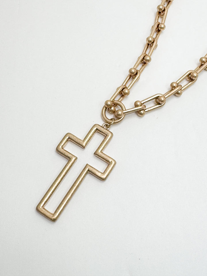 Gold cross necklace on a white background