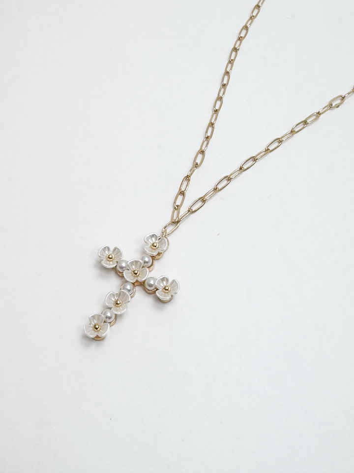 Gold necklace with a cross pendant featuring pearls on a white background