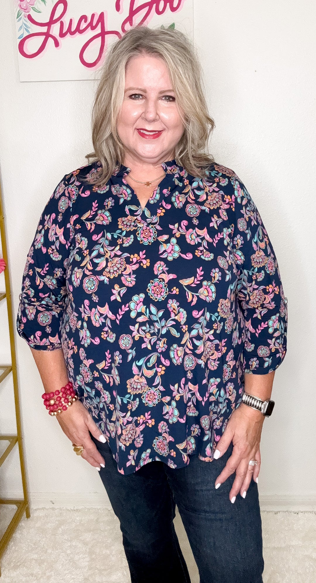 Woman wearing a navy floral blouse with a white background