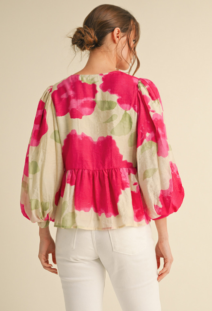 Woman wearing a floral blouse with pink and green patterns on a beige background