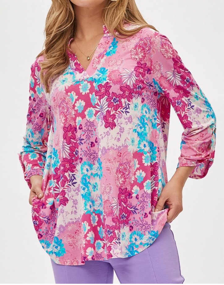 Woman wearing a long-sleeve floral blouse with pink, blue, and white flowers on a white background.