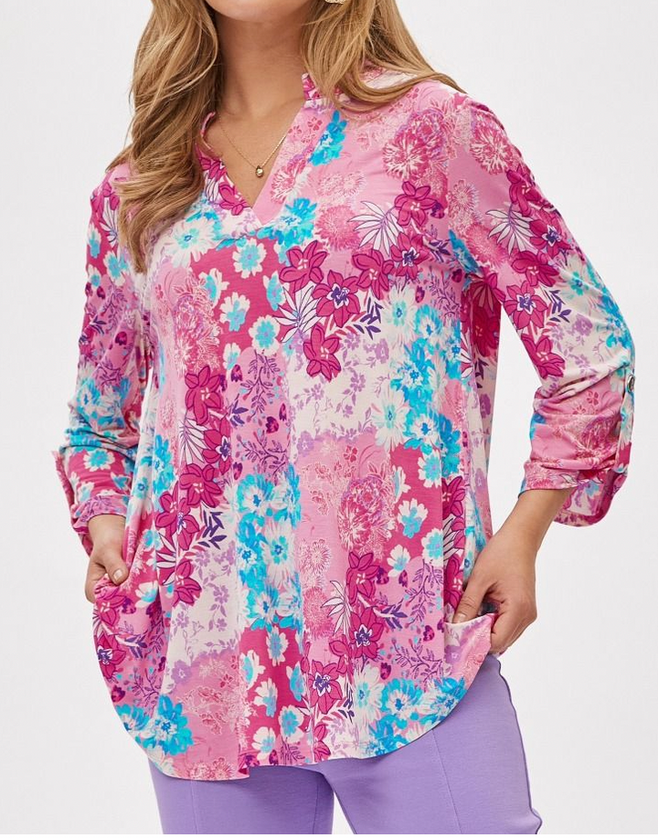 Woman wearing a long-sleeve floral blouse with pink, blue, and white flowers on a white background.