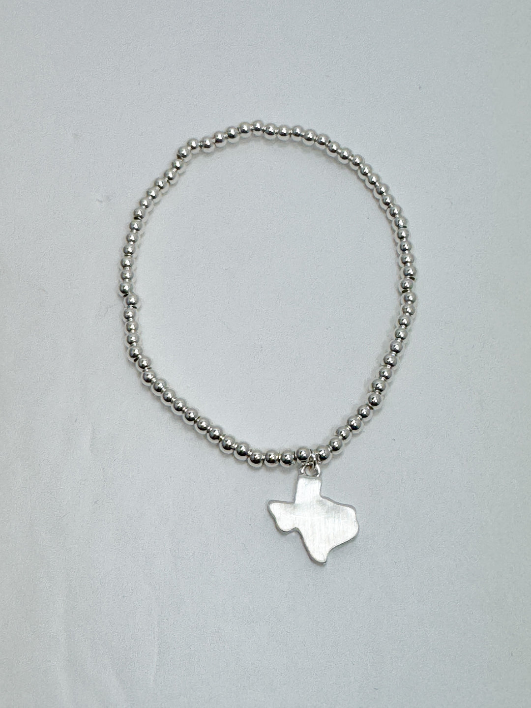 Silver beaded bracelet with a star-shaped charm on a light gray background