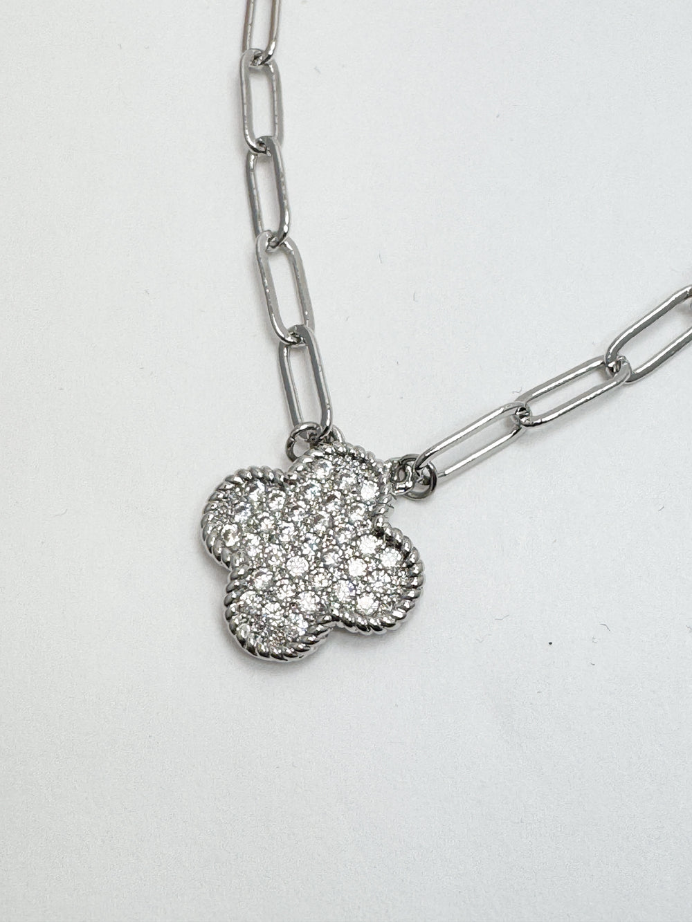Silver chain necklace with a clover-shaped pendant on a white background