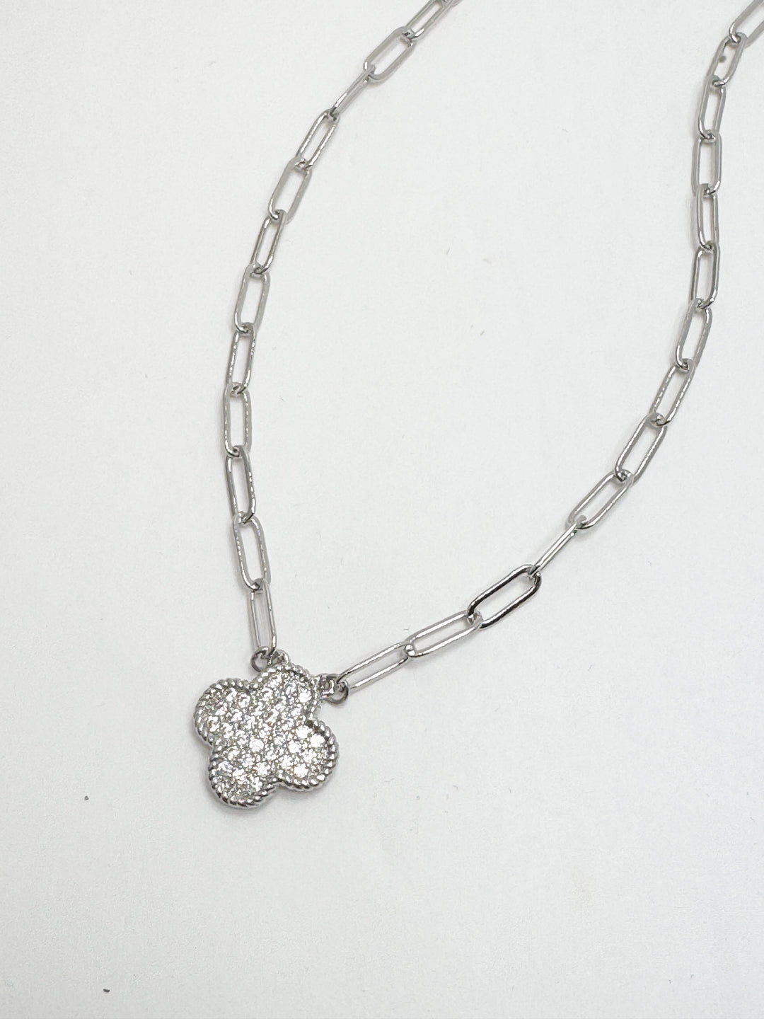 Silver chain necklace with a clover-shaped pendant on a white background