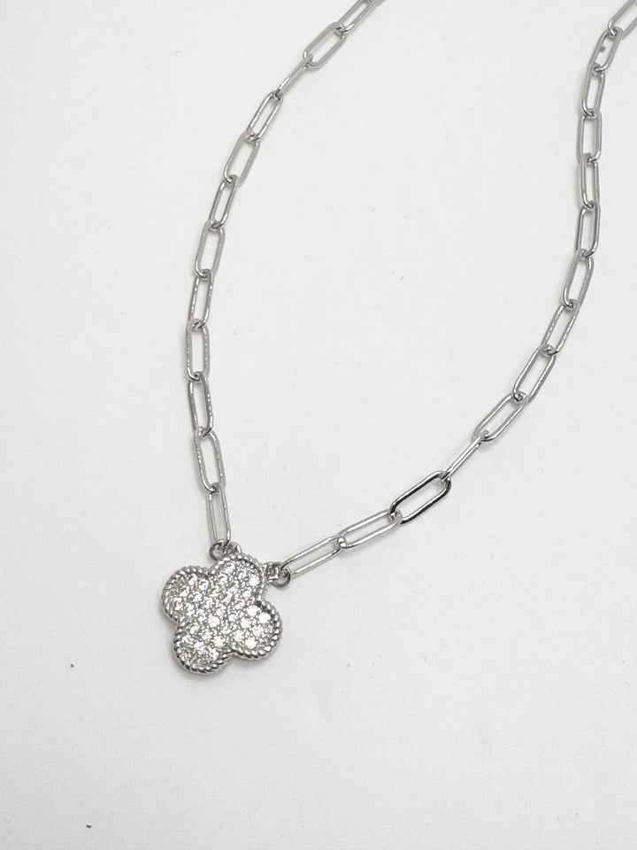 Silver chain necklace with a clover-shaped pendant on a white background