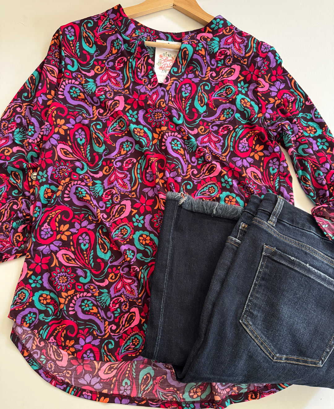 Colorful paisley-patterned shirt and blue jeans on a white background