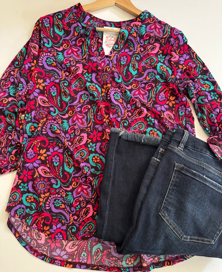Colorful paisley-patterned shirt and blue jeans on a white background