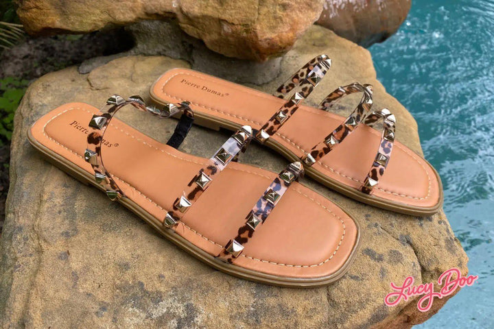 animal print sandals on rocks beside swimming pool