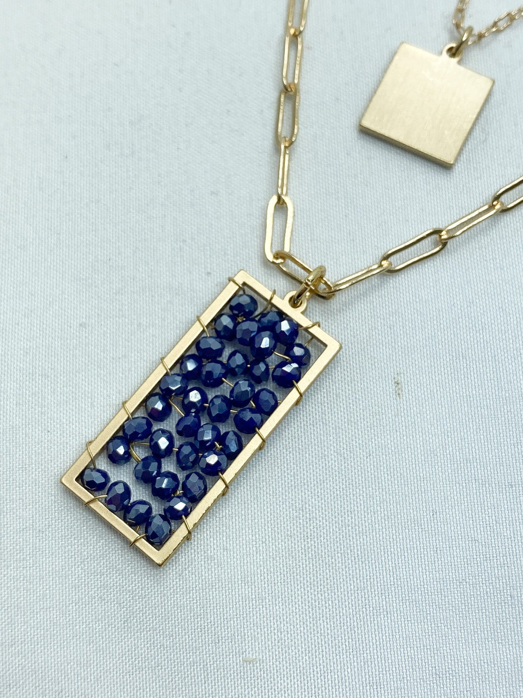 Layered Gold Necklace w/ Navy Blue Beaded Pendant  on white background