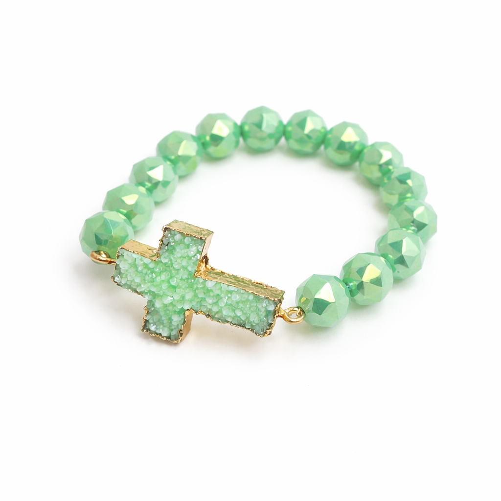 Green beaded bracelet with a gold cross charm on a white background