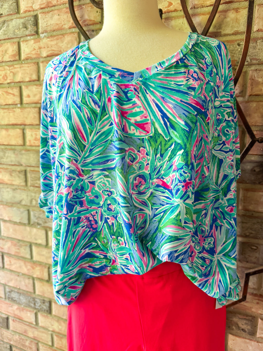 Colorful patterned top on a mannequin against a brick wall.