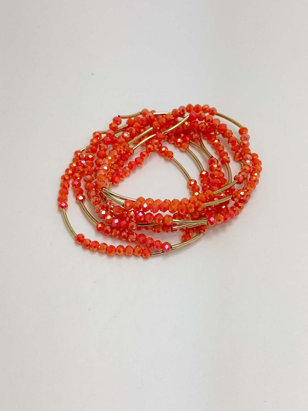 A set of orange and gold beaded bracelets on a white background