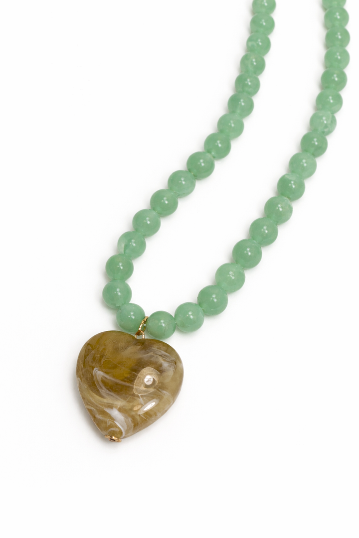 Necklace with green beads and a heart-shaped pendant on a white background