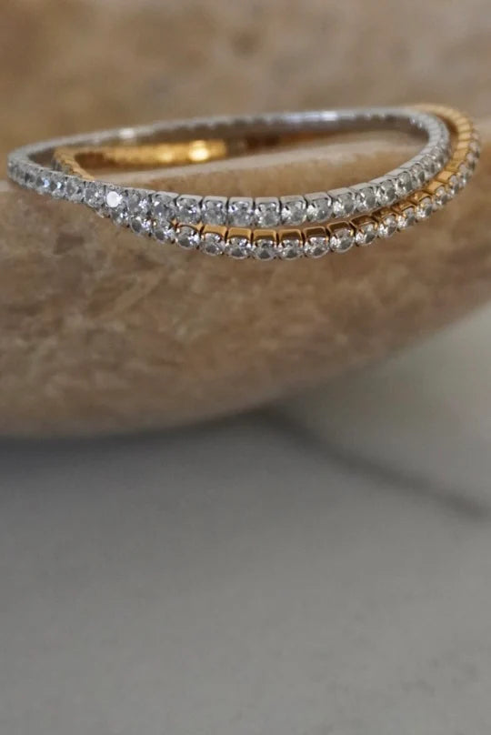 Two gold and silver bangles on a textured surface