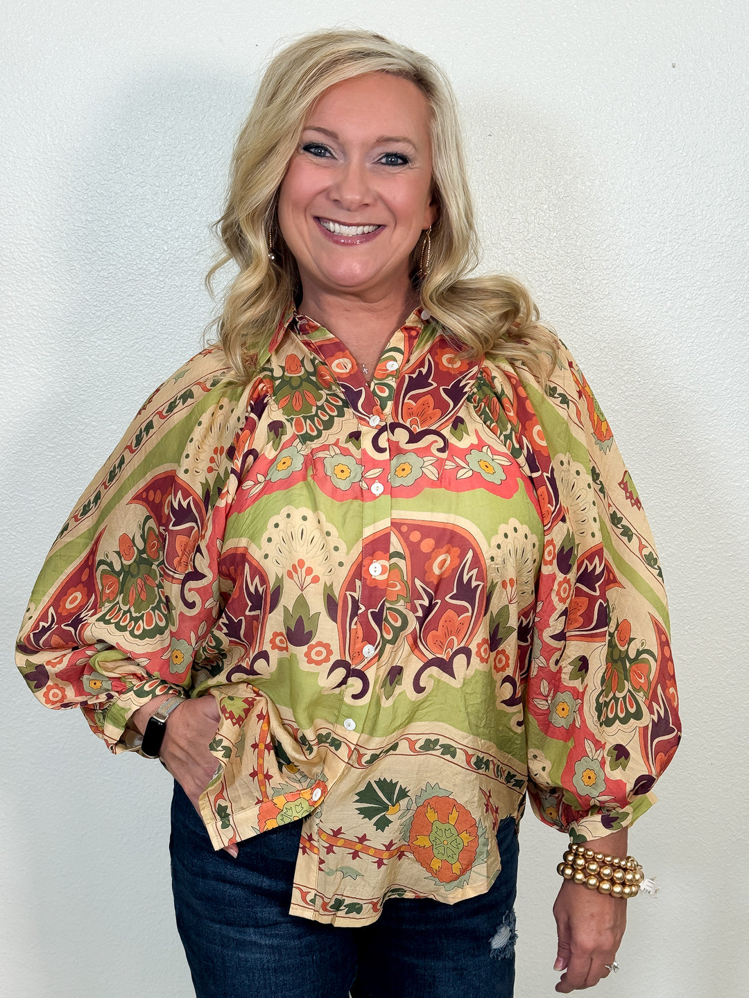 Woman wearing a colorful patterned blouse against a white background