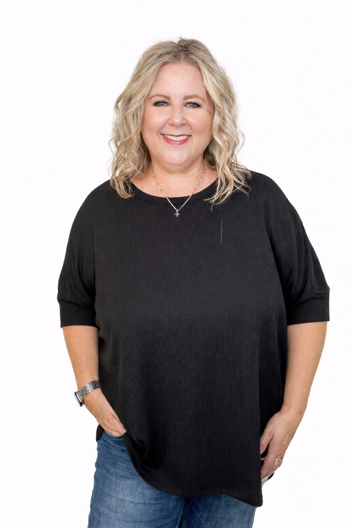 Woman wearing a black oversized sweater and blue jeans on a white background