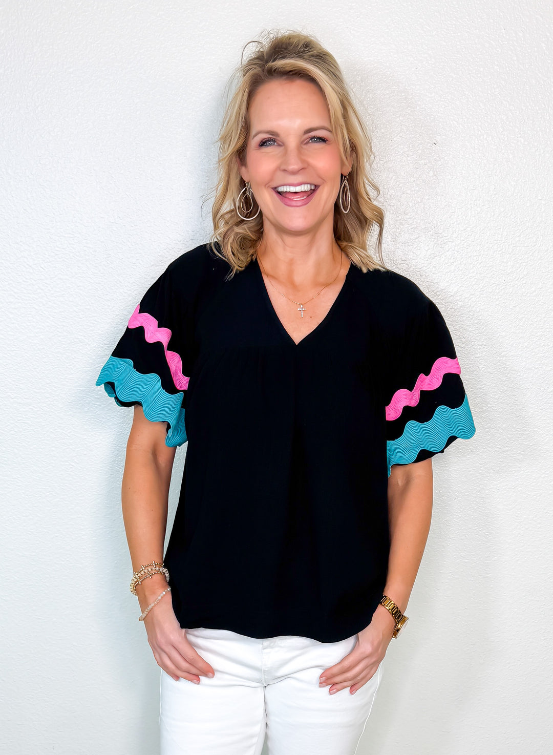 Woman wearing a black top with colorful sleeves against a white background