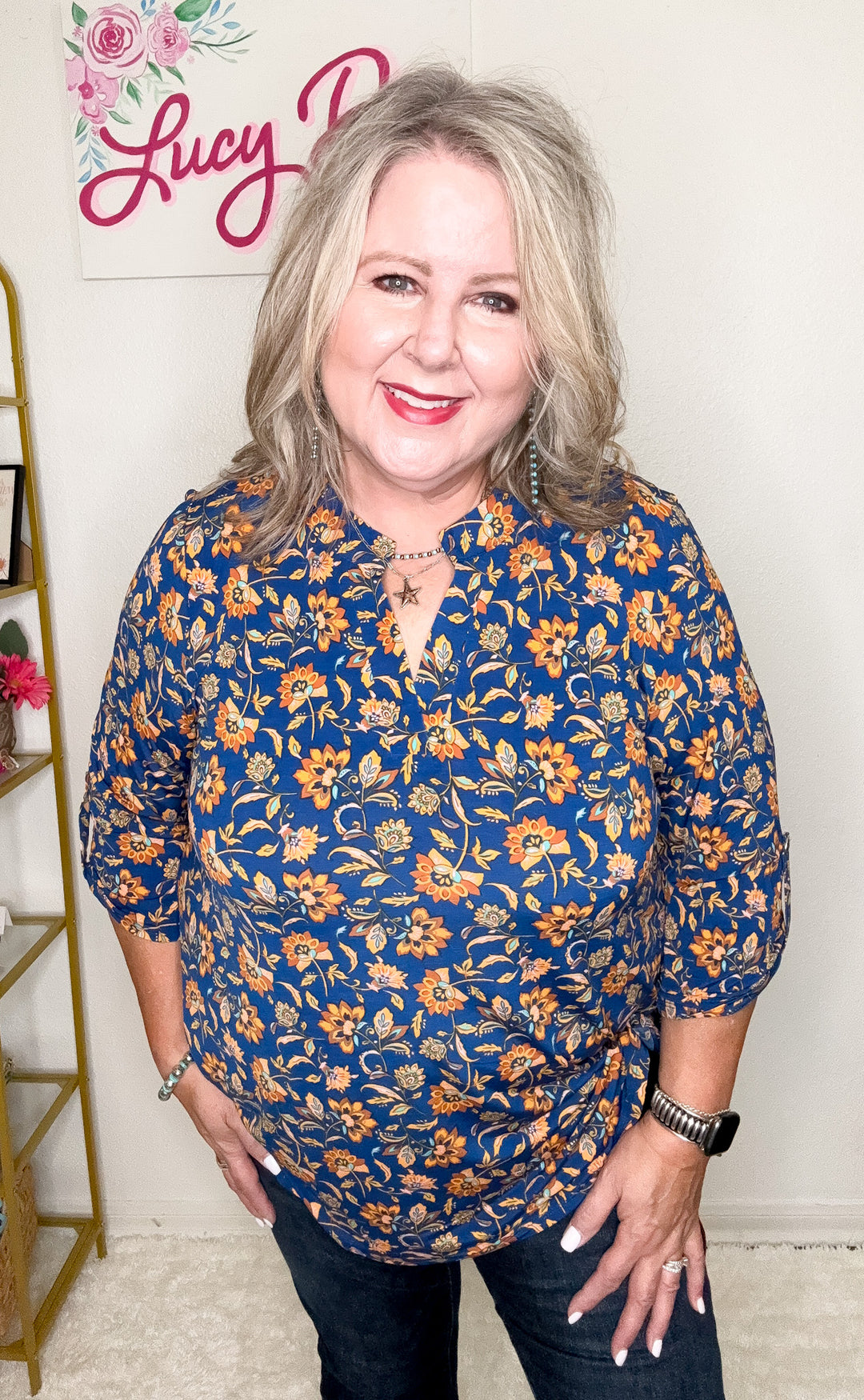 Woman wearing a blue floral blouse with a decorative background