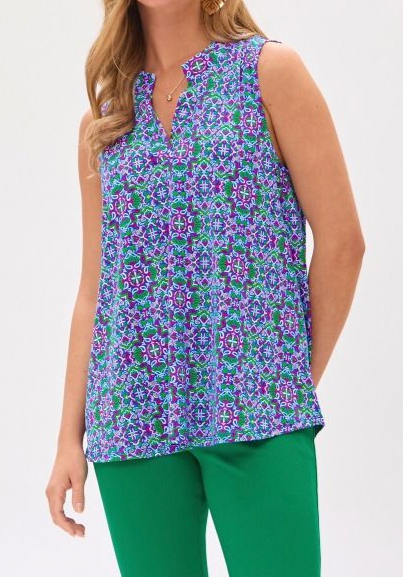 Woman wearing a sleeveless floral top and green pants on a white background