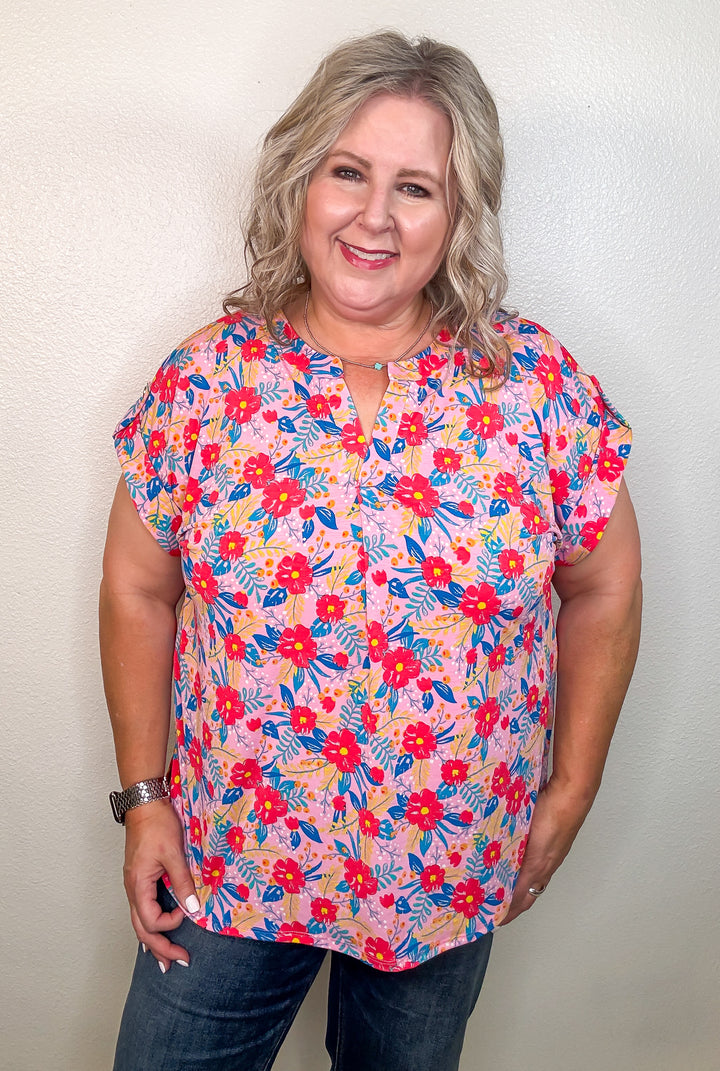 Woman wearing a colorful floral blouse against a plain background