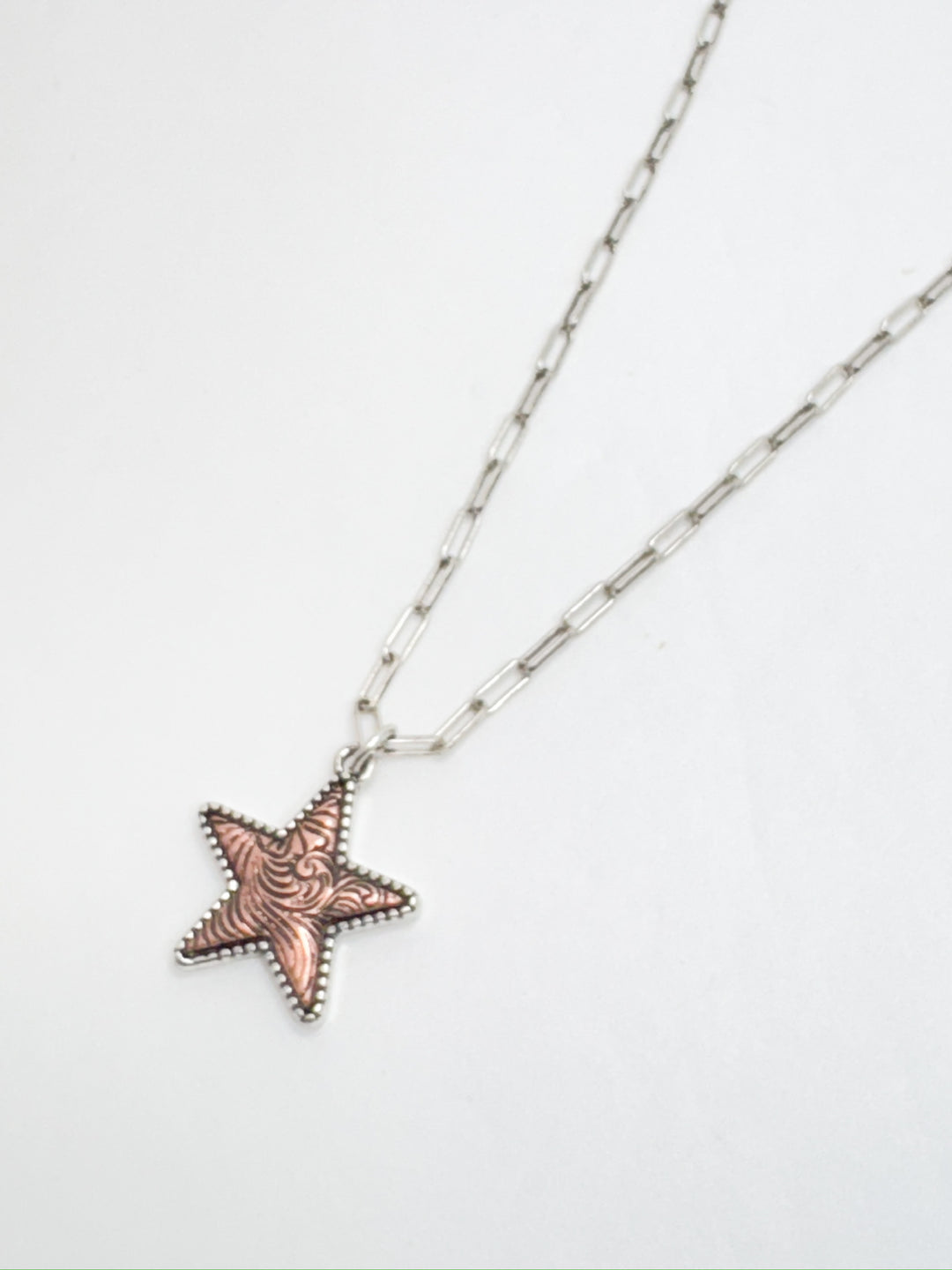 A silver necklace with a teardrop-shaped iridescent pendant and a silver star charm, displayed against a white background.
