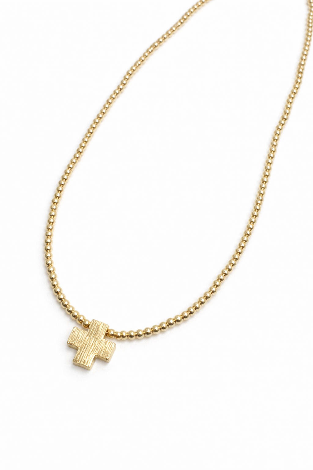 Gold necklace with a small cross pendant on a white background