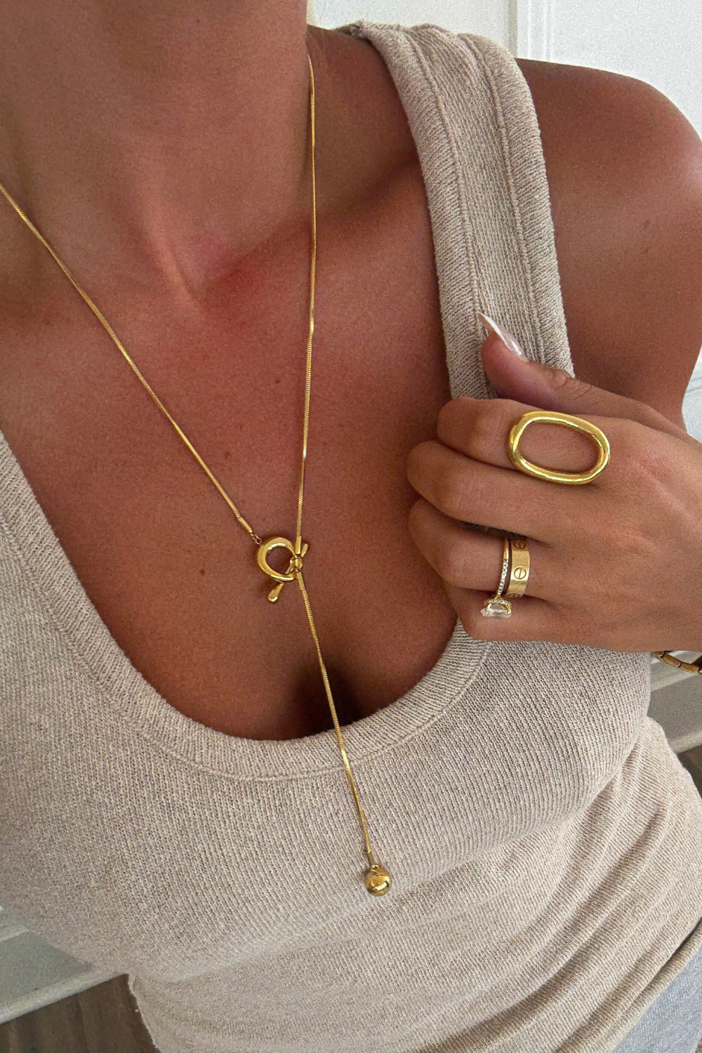 Close-up of a person wearing gold jewelry including a necklace and rings.