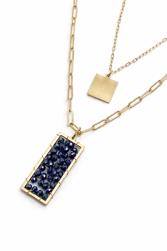 Gold necklace with a blue gemstone pendant on a white background