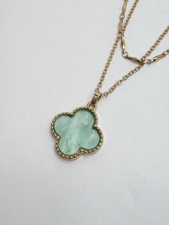 Necklace with a green clover-shaped pendant on a white background