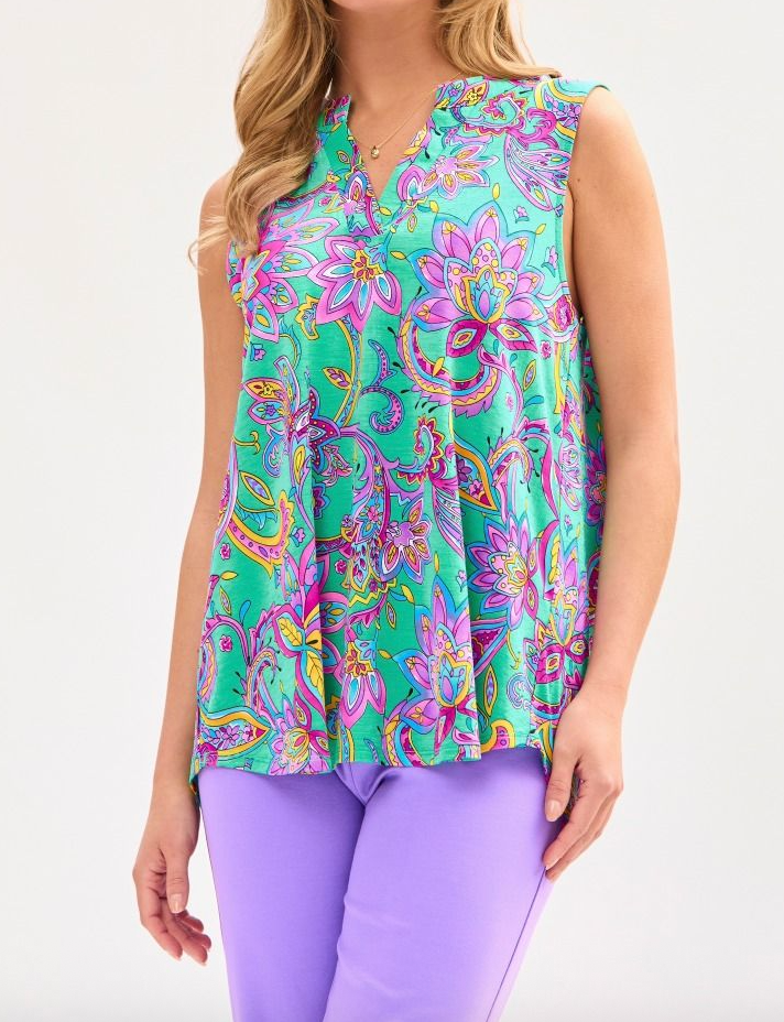Woman wearing a colorful floral sleeveless top and purple pants on a white background