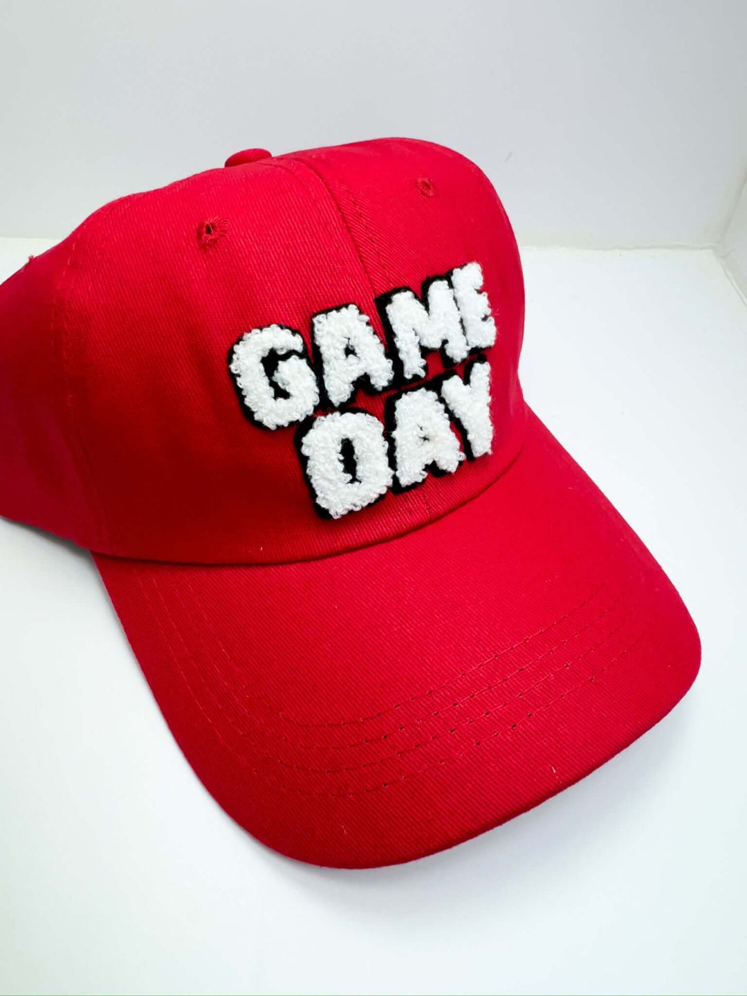 A red baseball cap with 'Game Day' text embroidered in white on the front.