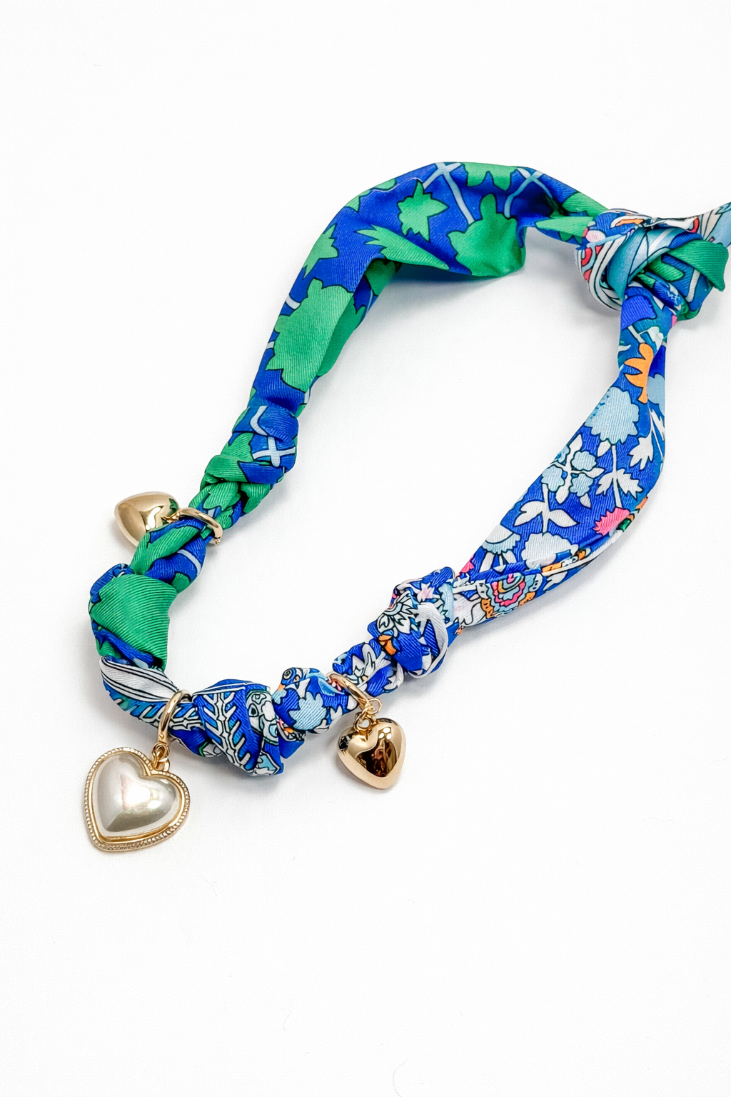 Colorful floral-patterned headband with heart-shaped charms on a white background