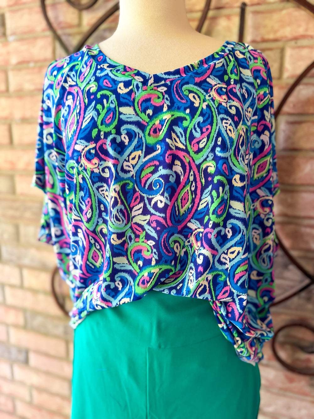 Colorful patterned top on a mannequin against a brick wall background