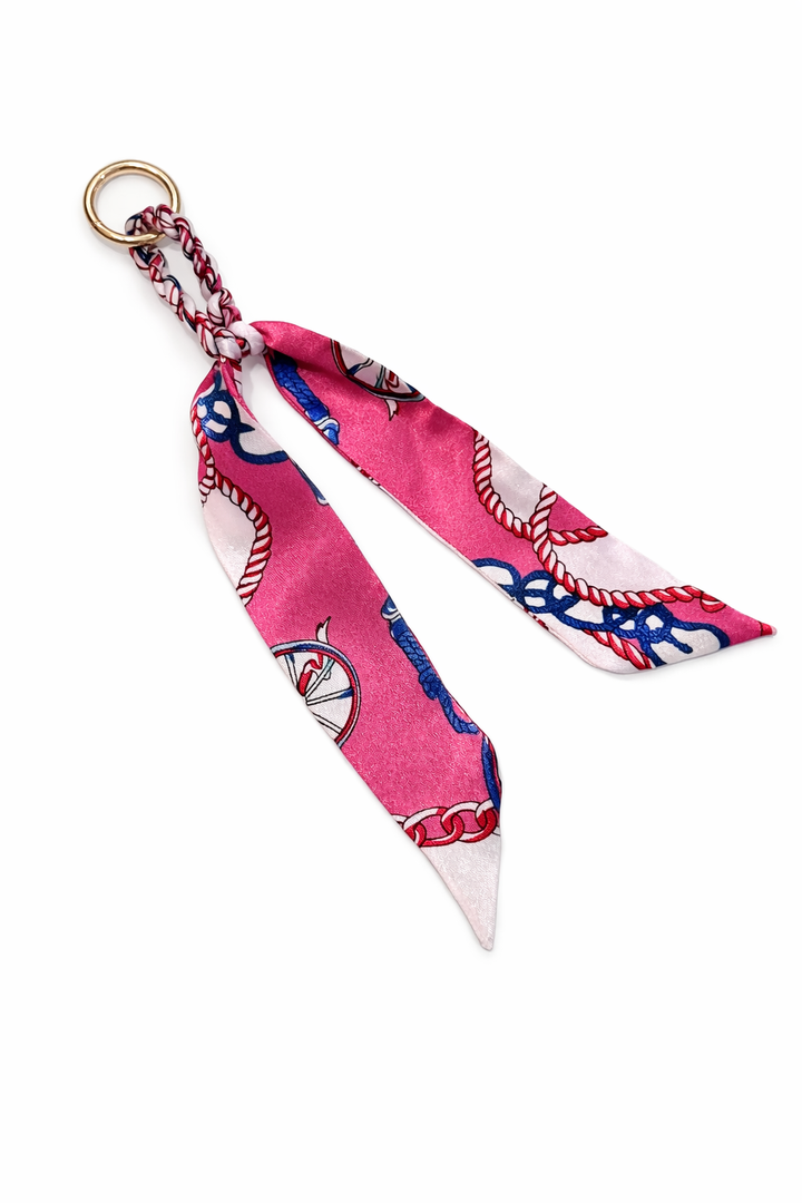 Pink scarf with blue and white patterns tied into a bow on a white background