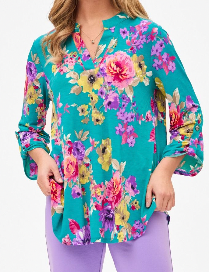 Woman wearing a teal floral blouse with colorful flowers on a white background